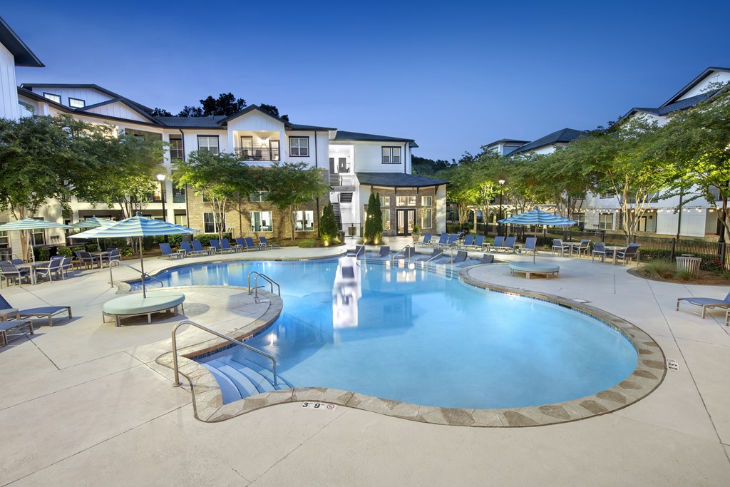 A large swimming pool surrounded by lounge chairs and umbrellas at a resort.
