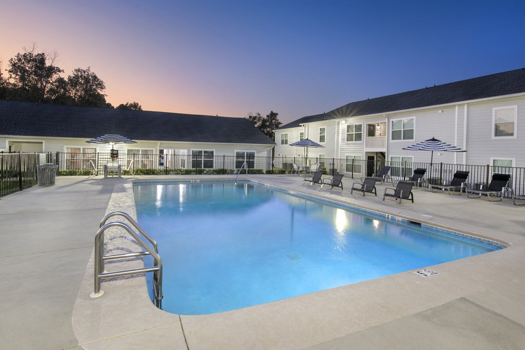a swimming pool with chairs and umbrellas in front of a building