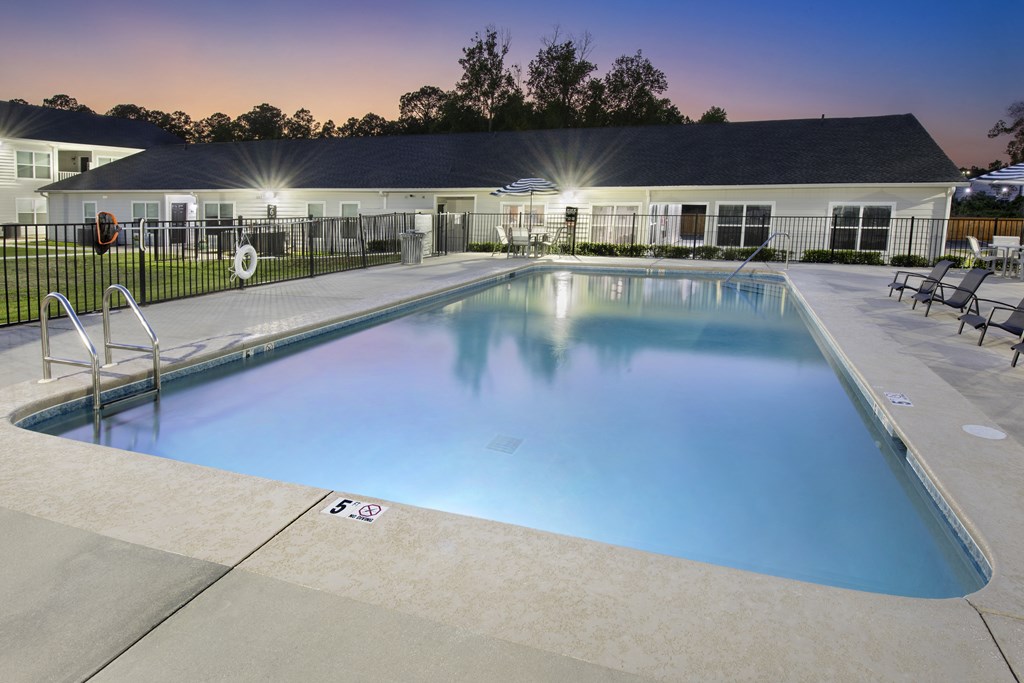 a swimming pool with chairs and a building in the background