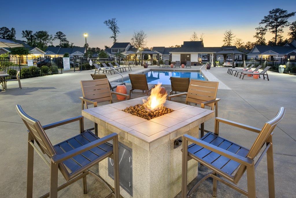 an outdoor patio with a fire pit and chairs