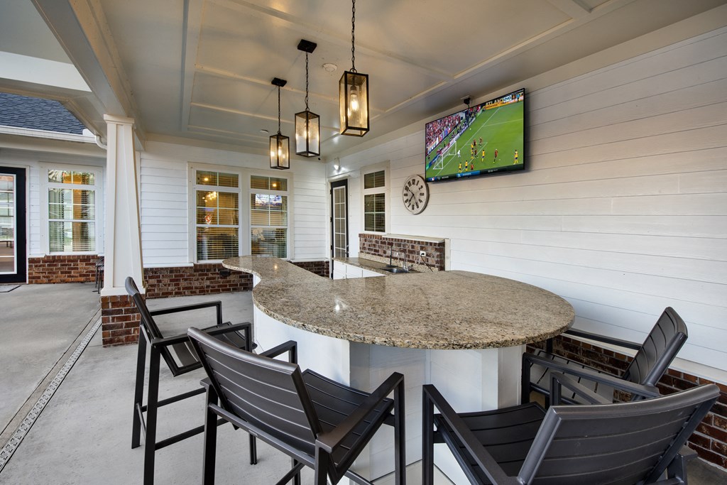 a kitchen with a bar with chairs and a tv