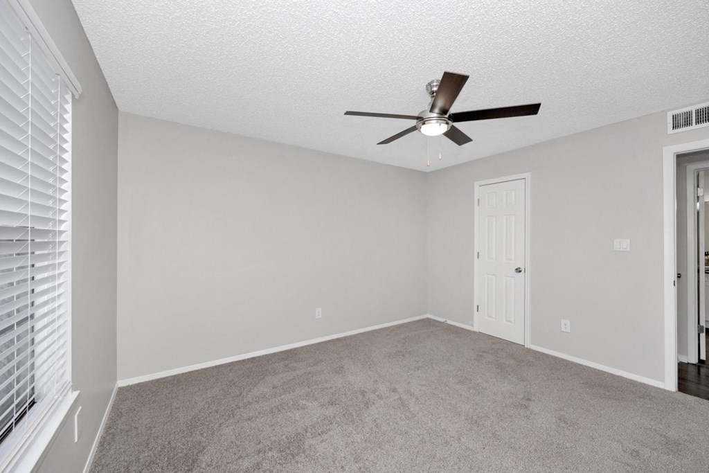 A room with a ceiling fan and carpeted floor.