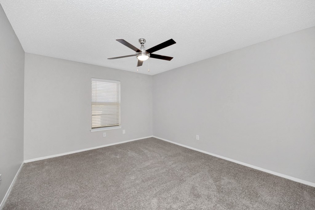 A room with a ceiling fan and carpeted floor.