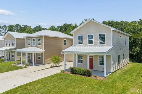 A house with a red door is in front of a house with a brown door.