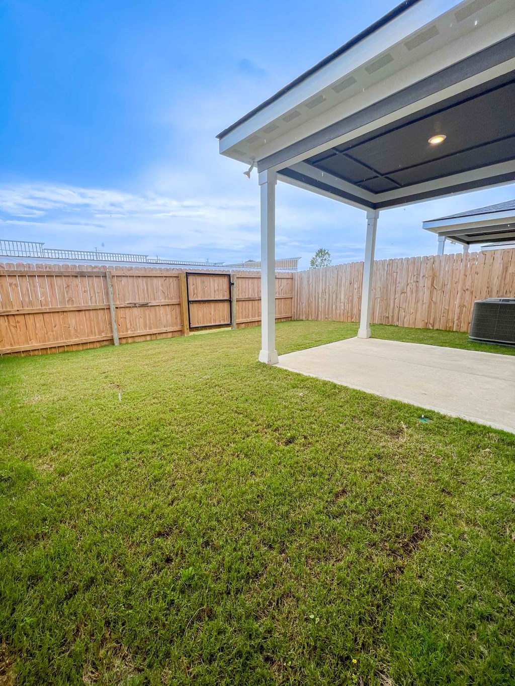 a backyard with a patio and a fence and grass