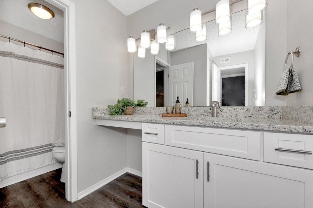 A bathroom with a vanity, mirror, and lights.