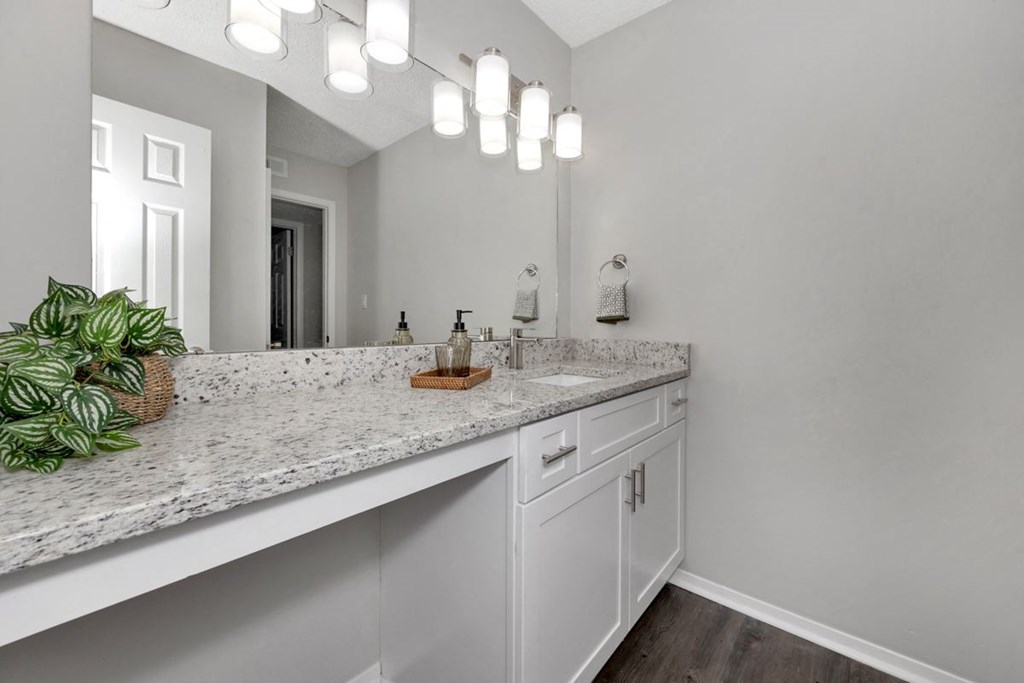 A bathroom with a marble countertop and white cabinets.
