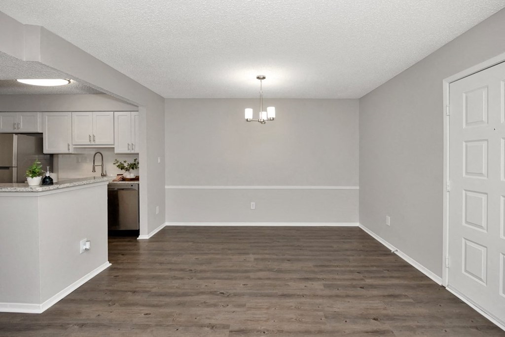 A kitchen with white cabinets and a wooden floor.
