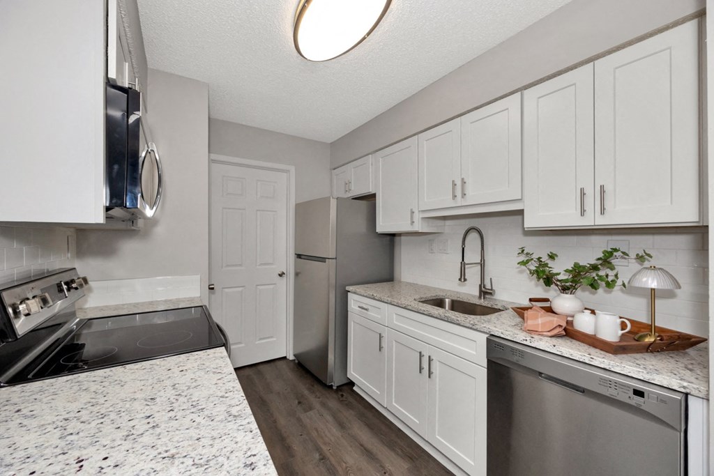 A kitchen with white cabinets and a marble countertop.