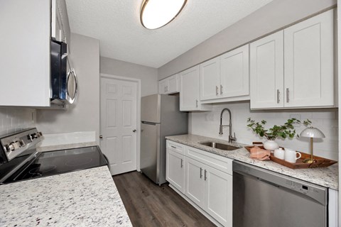 A kitchen with white cabinets and a marble countertop.