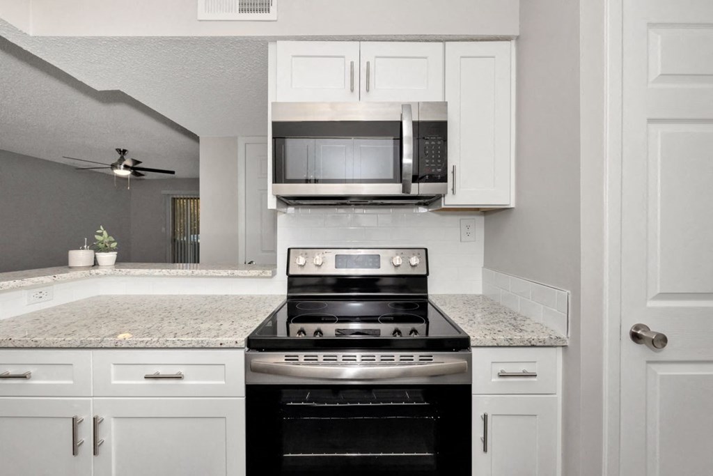 A black stove top oven in a kitchen with white cabinets.