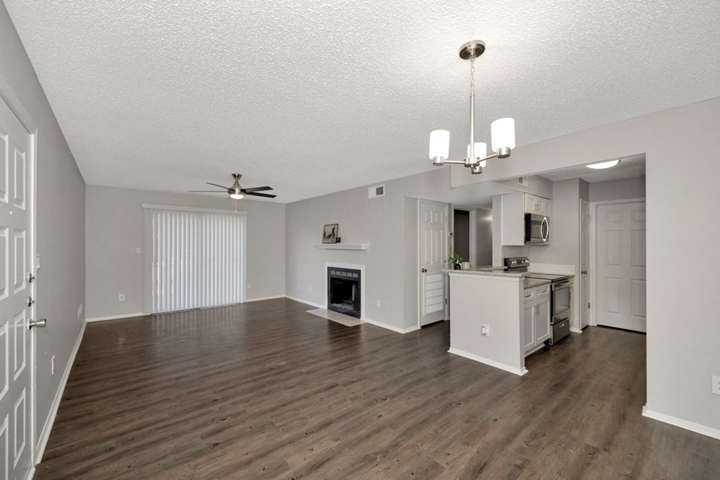 A spacious living room with a fireplace and a kitchen area in the background.