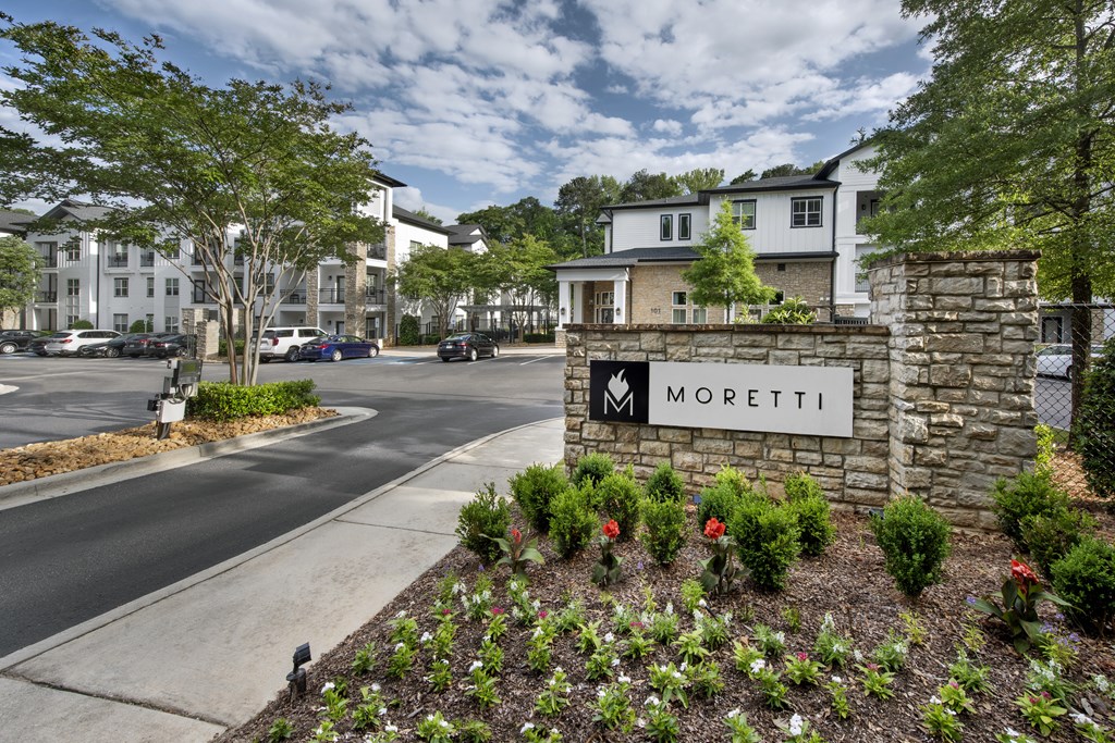 A street view of Moretti apartments with a stone entrance sign.