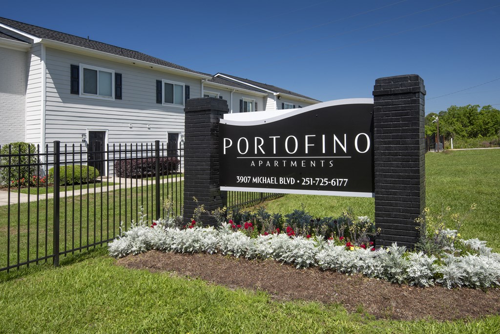 the sign in front of a property with a fence and flowers