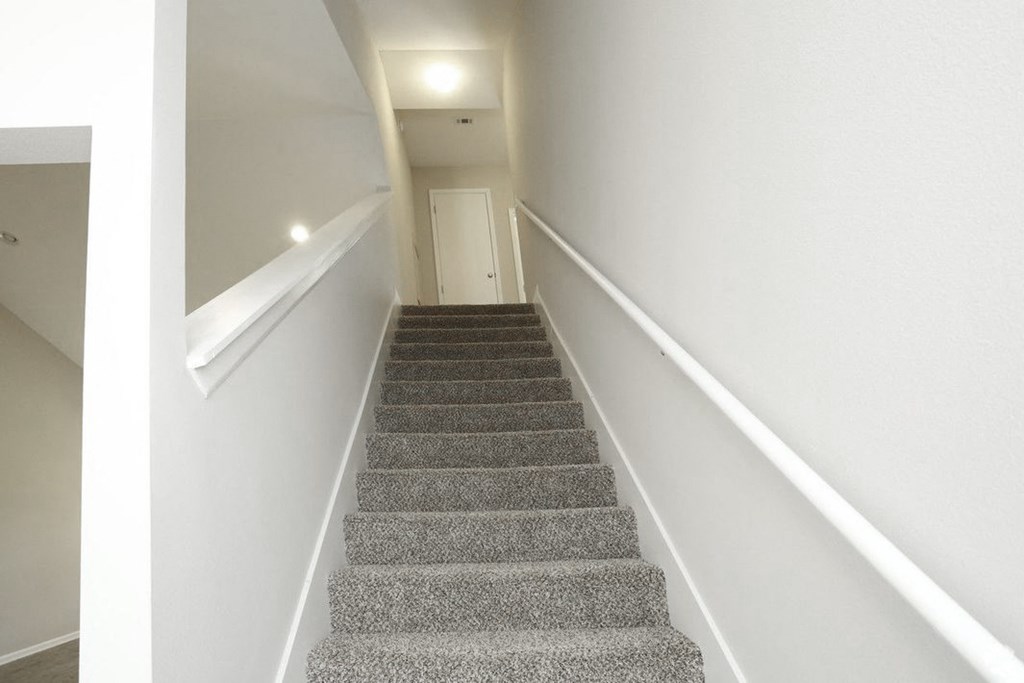 a staircase with gray carpet and white walls and a white door