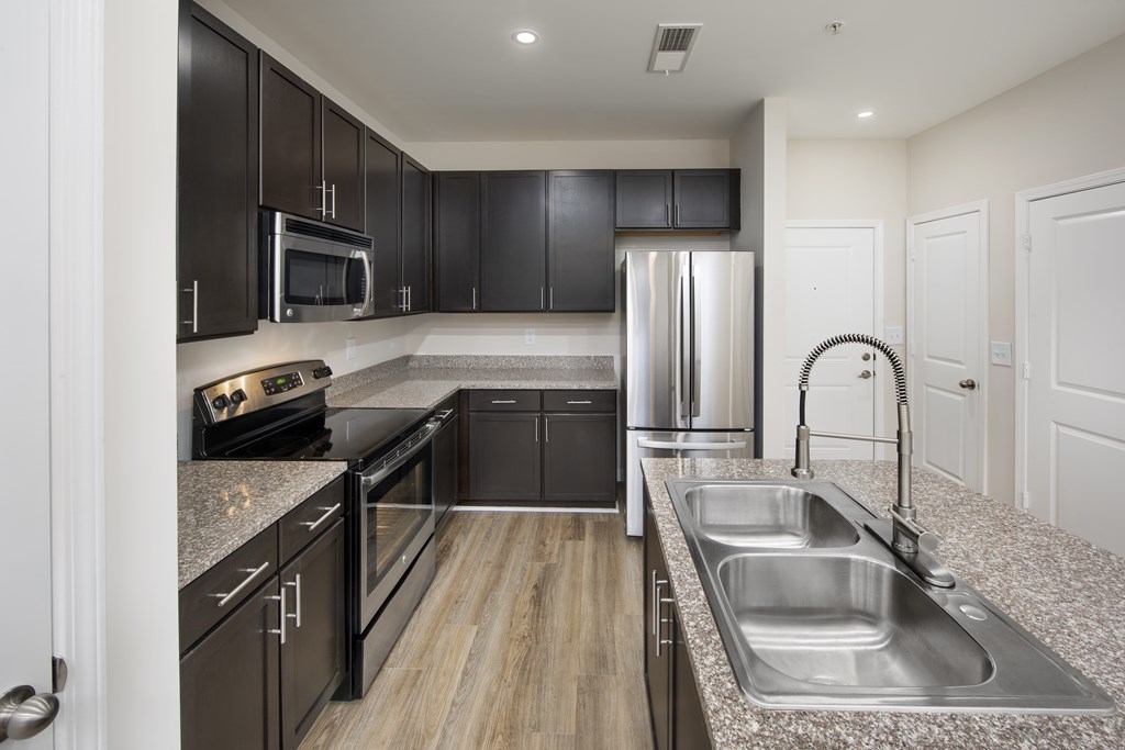 A modern kitchen with black cabinets and stainless steel appliances.