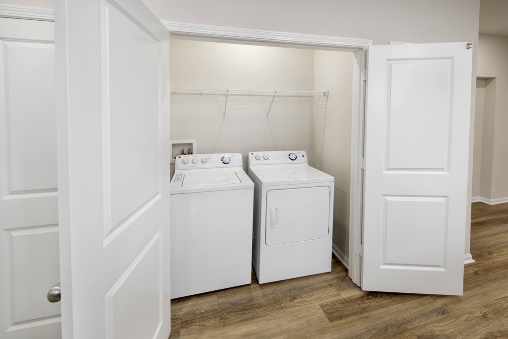 A white door is open to a laundry room with two washing machines.