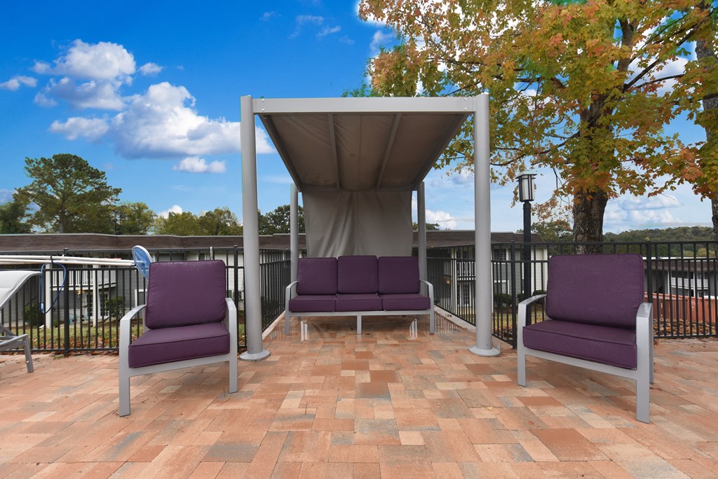 two purple chairs sitting under a canopy on a patio