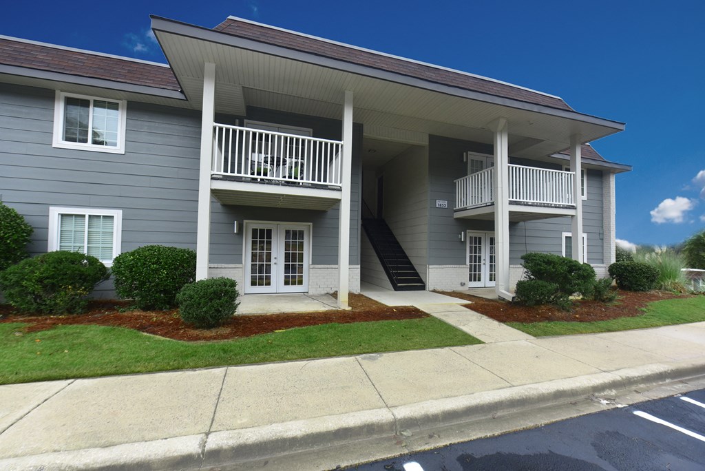 a white house with a balcony and a sidewalk