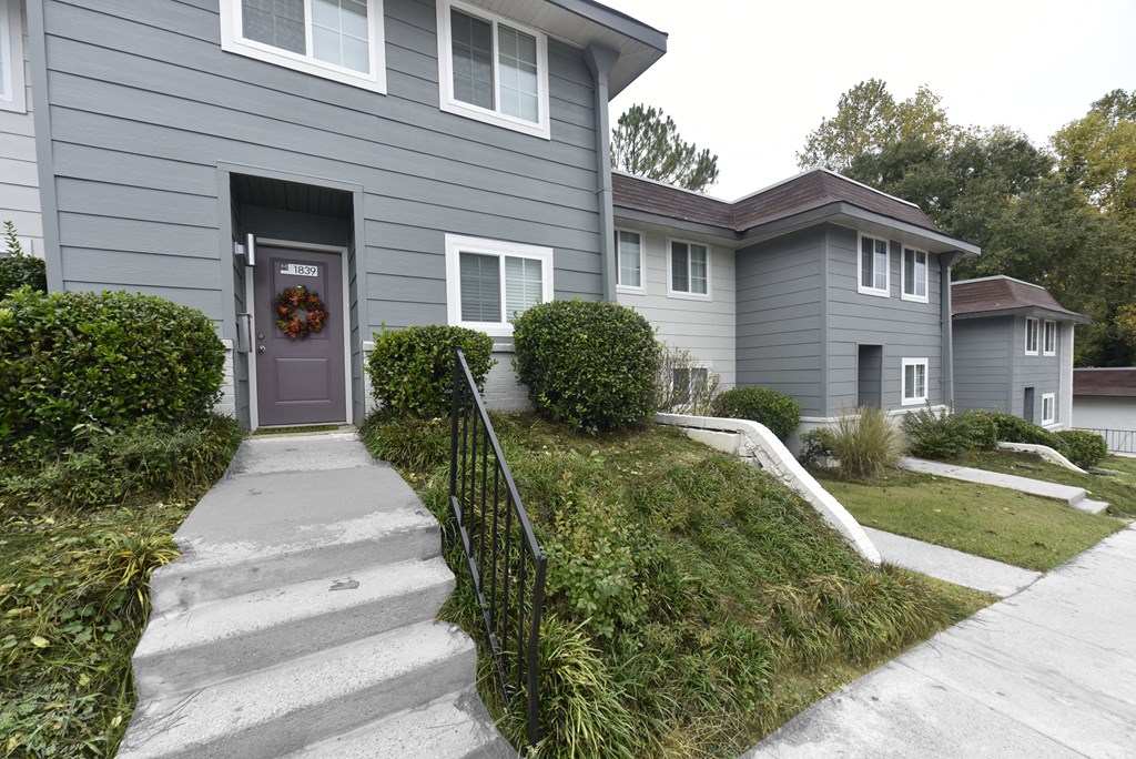 the front of a gray house with a purple door