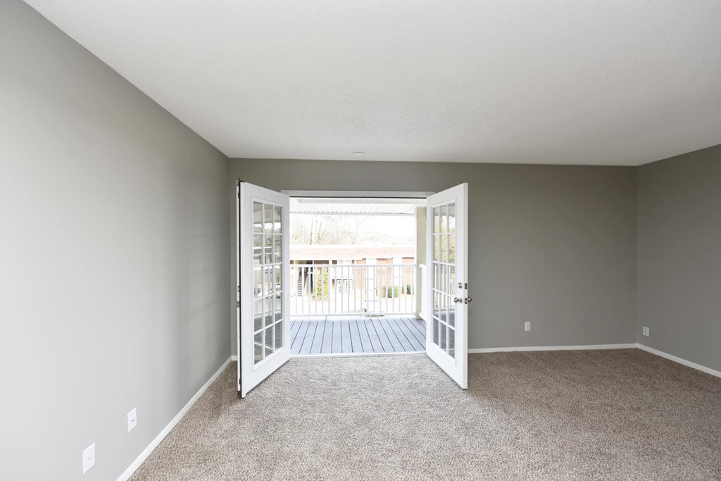 an empty living room with open doors to a balcony