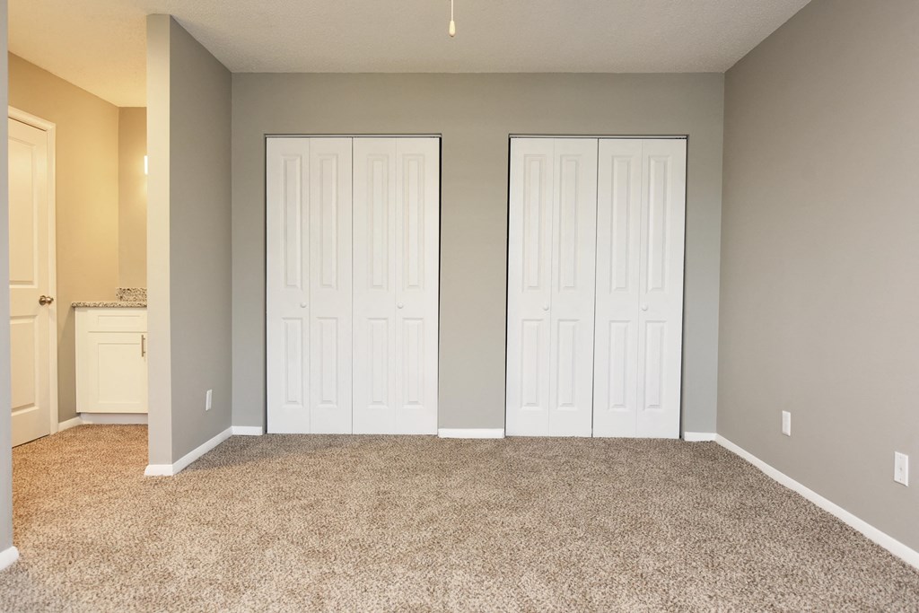 an empty room with three doors and a carpeted floor