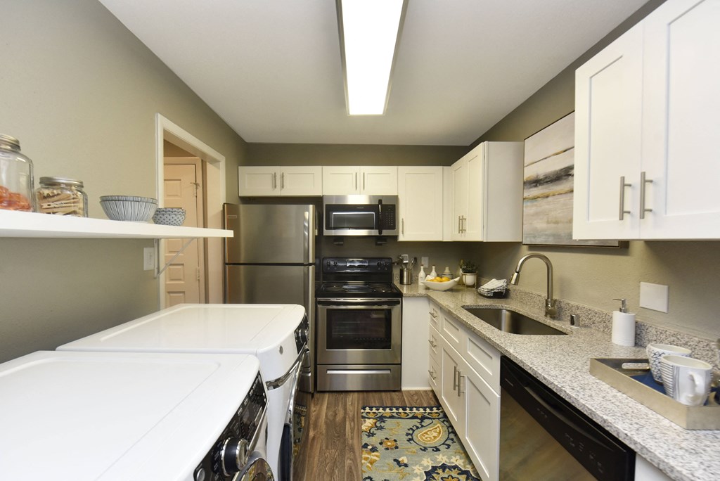 a kitchen with white counter tops and stainless steel appliances
