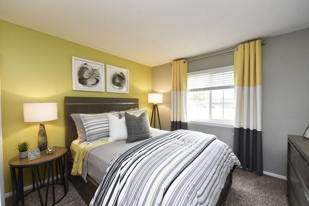 a bedroom with yellow walls and a bed with a striped comforter