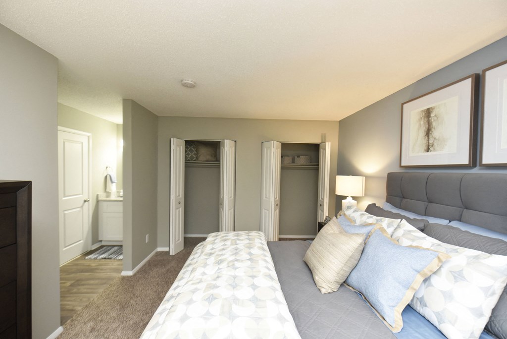 a bedroom with a large bed and a bathroom with closets