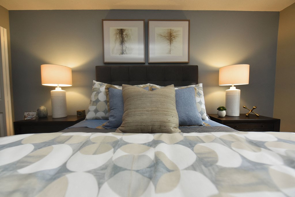 a bedroom with a bed with pillows and two lamps