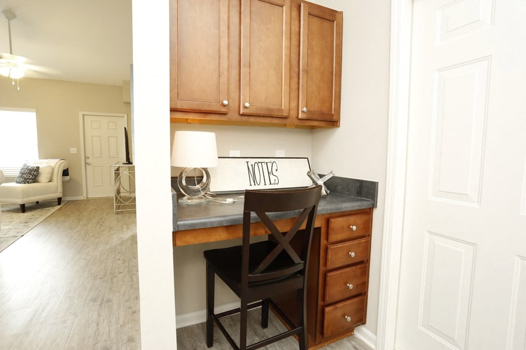 a small desk with a chair in a room with wooden cabinets