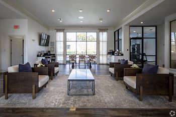 A spacious living room with a central coffee table and multiple seating options.