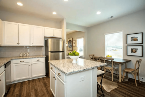 A kitchen with white cabinets and a granite countertop.