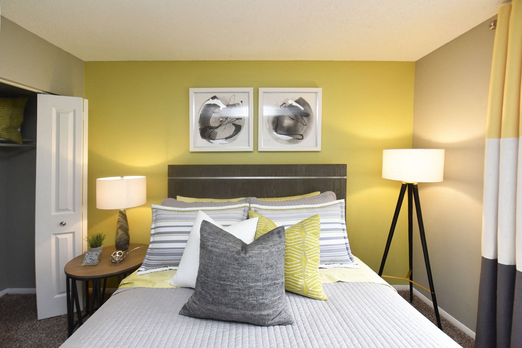 1-, 2-, & 3-Bedroom Apartments In Vestavia Hills, AL - MarQ Vestavia - Bedroom With Closet, Carpet Flooring, Modern Decor, Bed With Pillows, Floor Lamp, And Circle Nightstand With Desk Lamp.