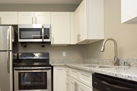 a kitchen with granite counter tops and white cabinets