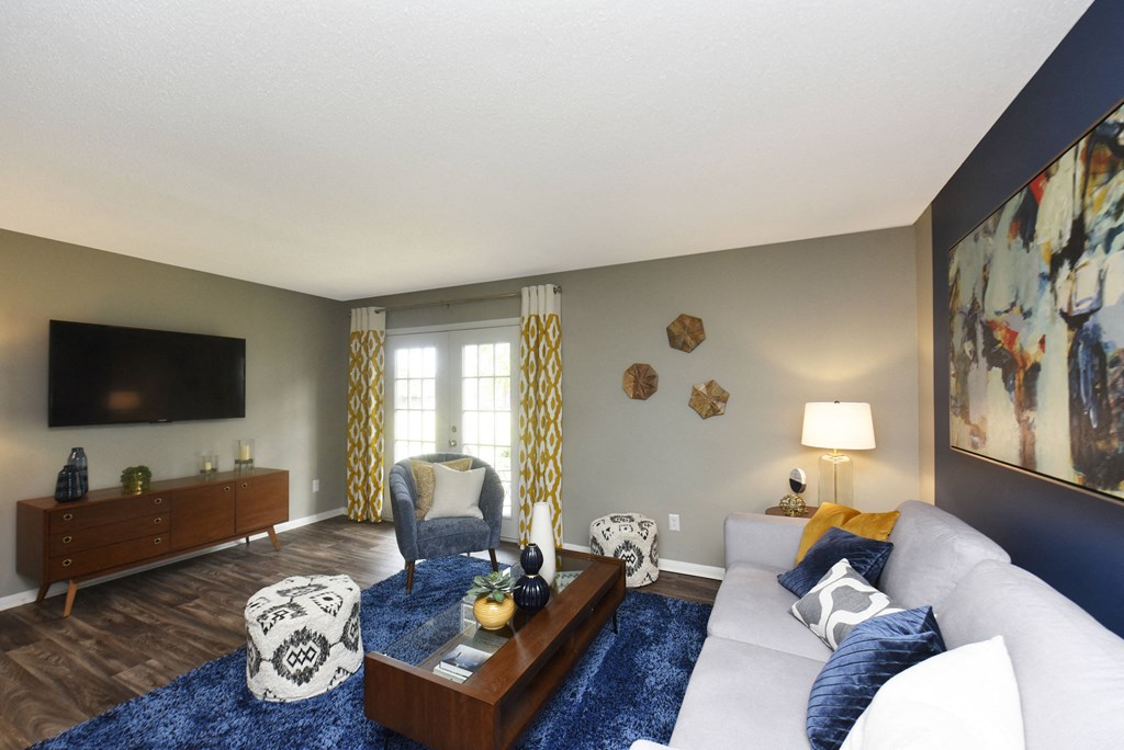 Vestavia Townhomes - MarQ Vestavia - Living Room With Chair, Couch, Modern Decor, TV, Wood-Style Flooring, Area Rug, Long Coffee Table, And French Windows