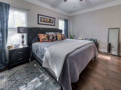 A bedroom with a large bed and a rug on the floor.
