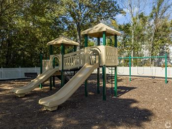 A playground with a yellow slide and a green roof.