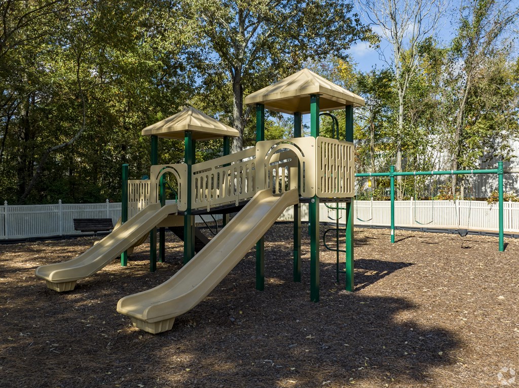 A playground with a yellow slide and a green roof.
