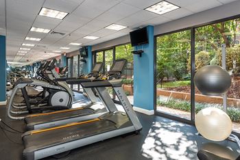 a gym with treadmills and other exercise equipment in a building with windows