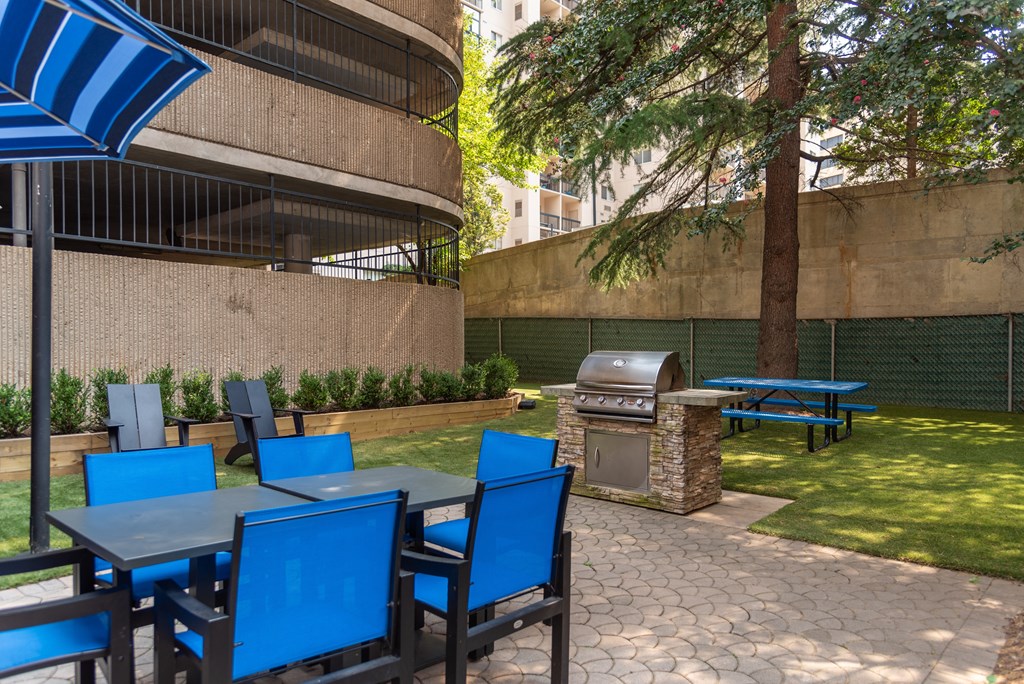 a patio with tables and chairs and a barbecue grill
