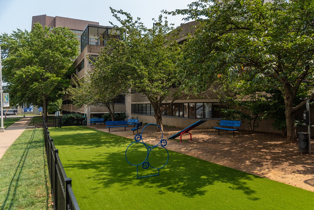 a playground with trees and benches in front of a building
