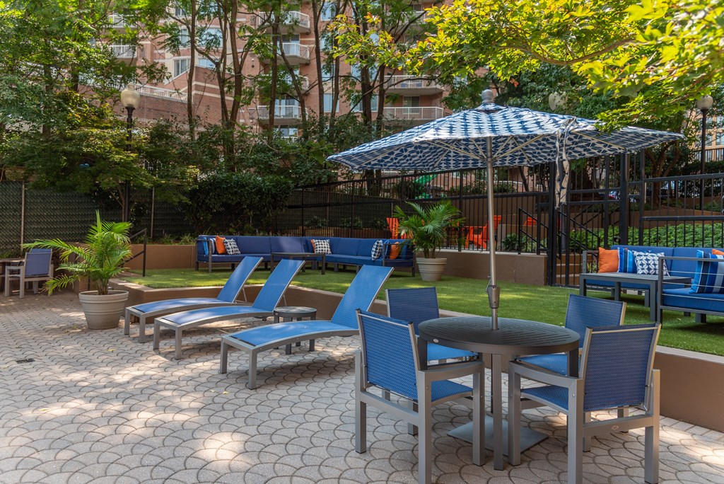 a patio with blue chairs and tables and an umbrella