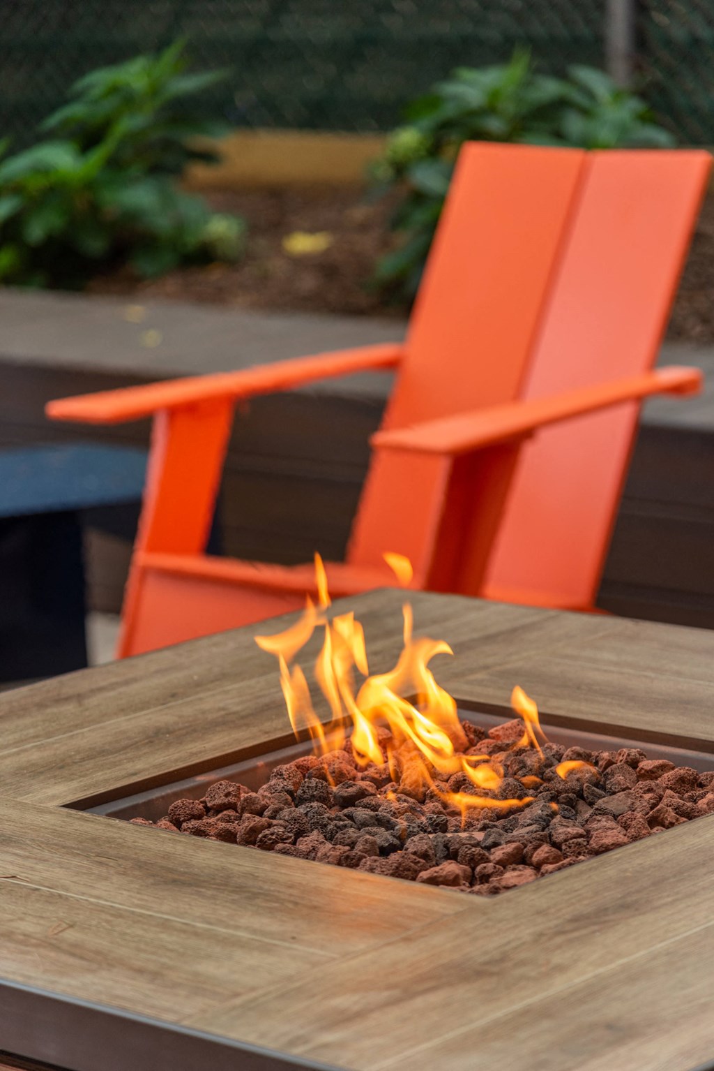 a fire pit on a wooden table with two orange chairs
