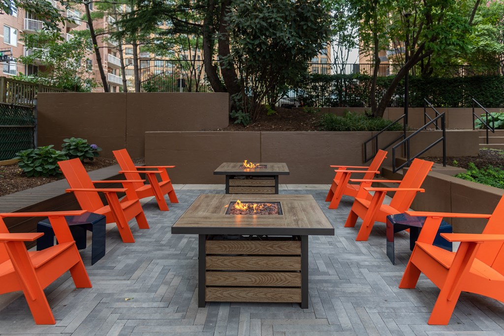 an outdoor patio with a fire table and orange chairs