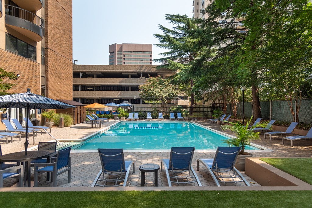 a swimming pool with blue chairs and a building in the background