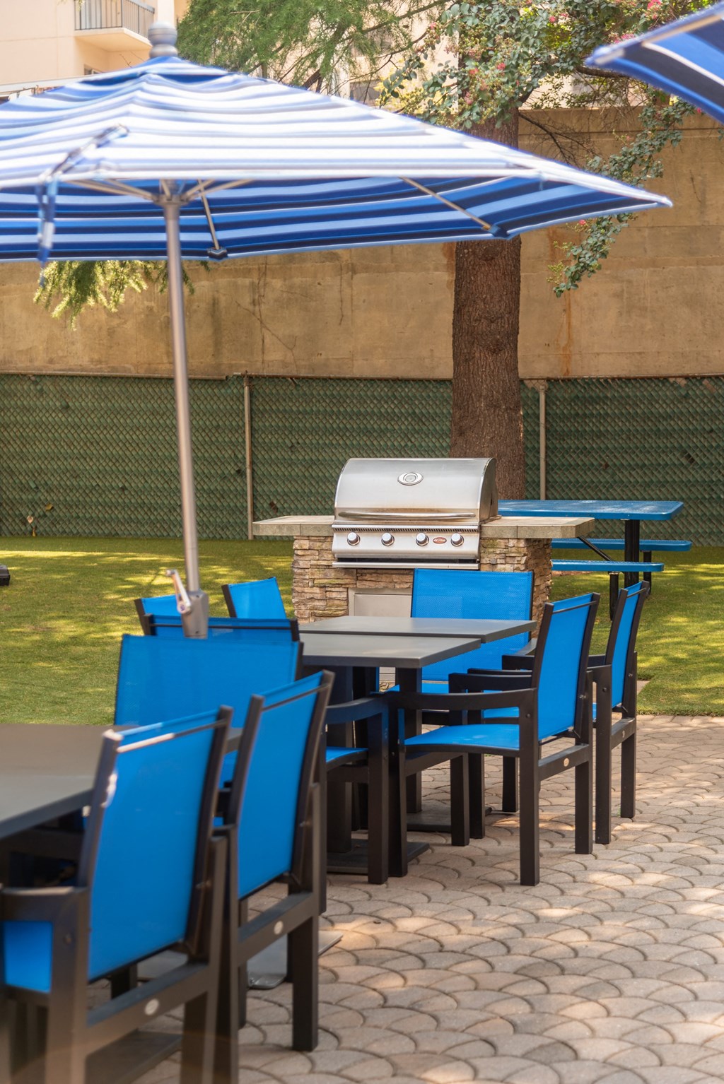 a patio with tables and chairs and an outdoor grill