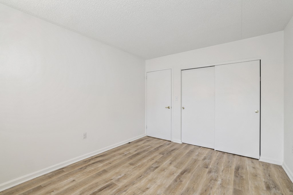 an empty room with white walls and wood flooring