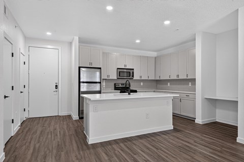 A kitchen with white cabinets and a wooden floor.