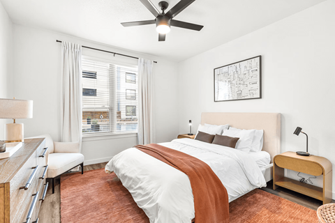 A bedroom with a bed, a chair, and a ceiling fan.
